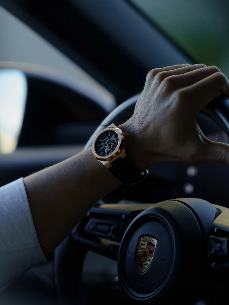 Mão ao volante de carro esportivo com relógio automático masculino CURTT Visionaire Rose no pulso